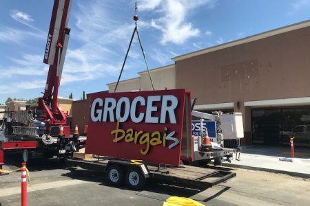 The new Grocery Outlet sign waits to be lifted into position.